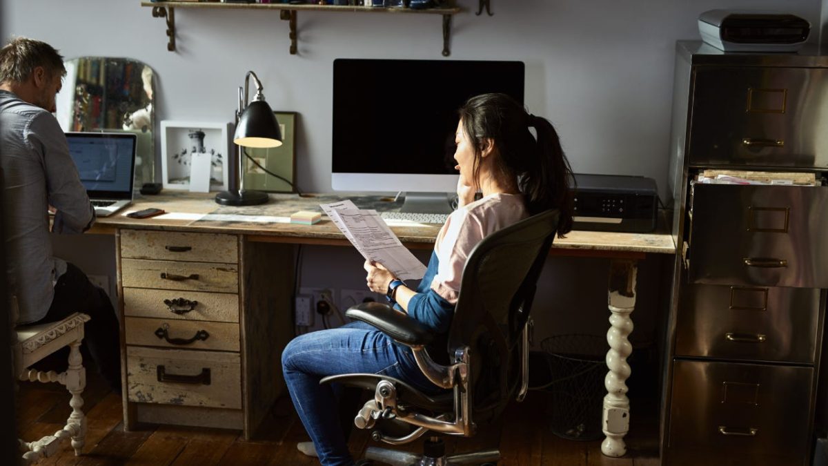 A woman is sitting in her home office on the phone with her auto insurance provider