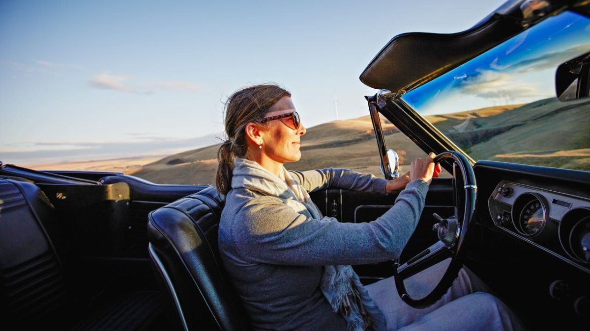 woman driving convertible at sunset